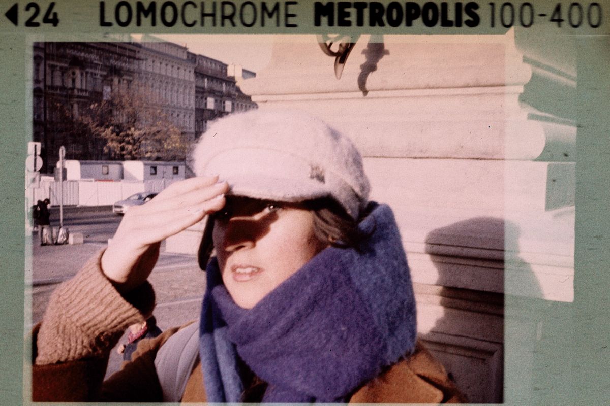 Analogue portrait of a young woman wearing a scarf and beanie, shot with a deliberately mismatched film format, the LomoChrome Metropolis film edge markings exposed onto the image. Unshielded by Gabriel Levi, Woman Portrait Gallery.