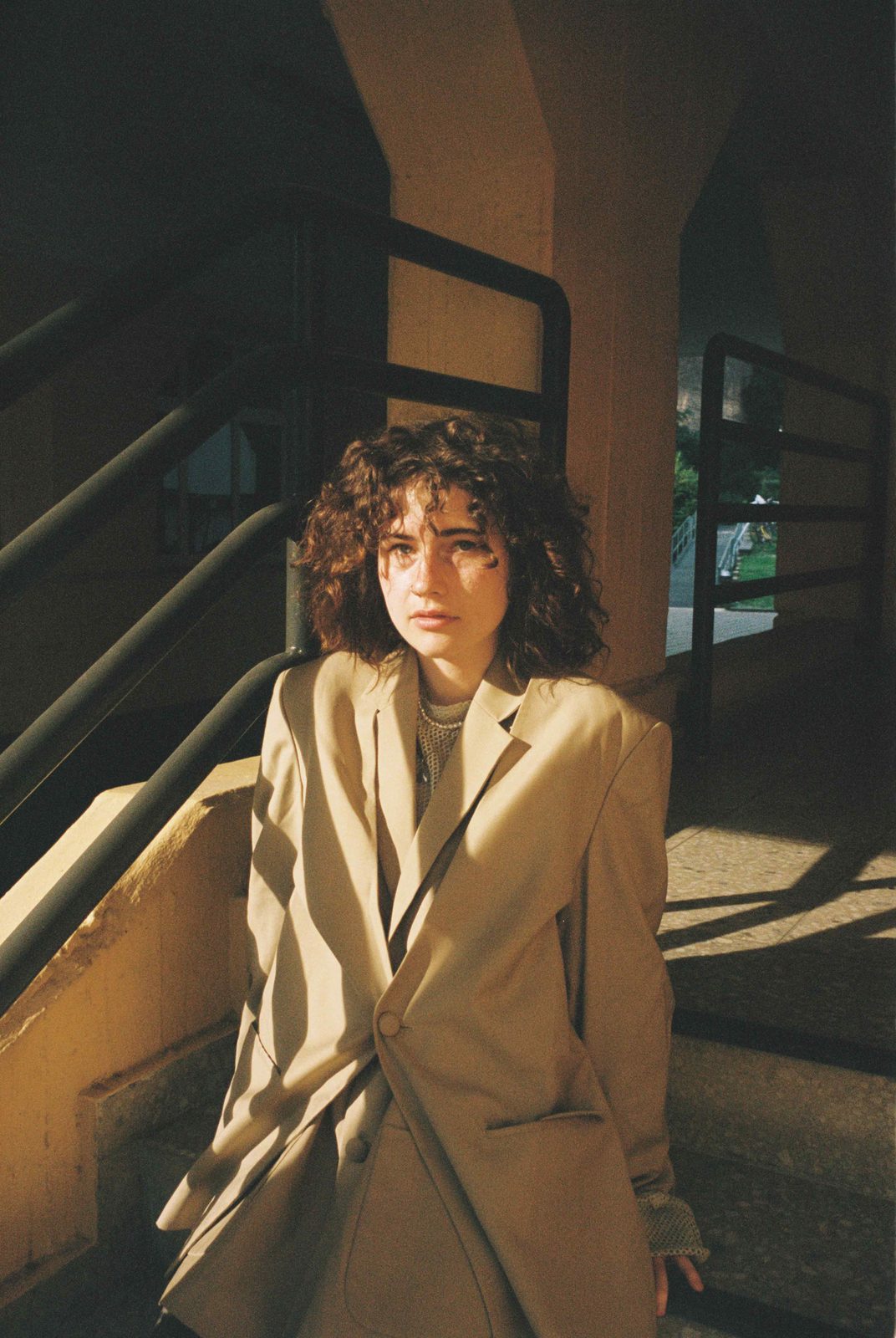 Analogue portrait on Kodak Gold film of a woman with curly hair wearing a blazer, bathed in warm natural light. Cora by Franka Suehlo, Woman Portrait Gallery.